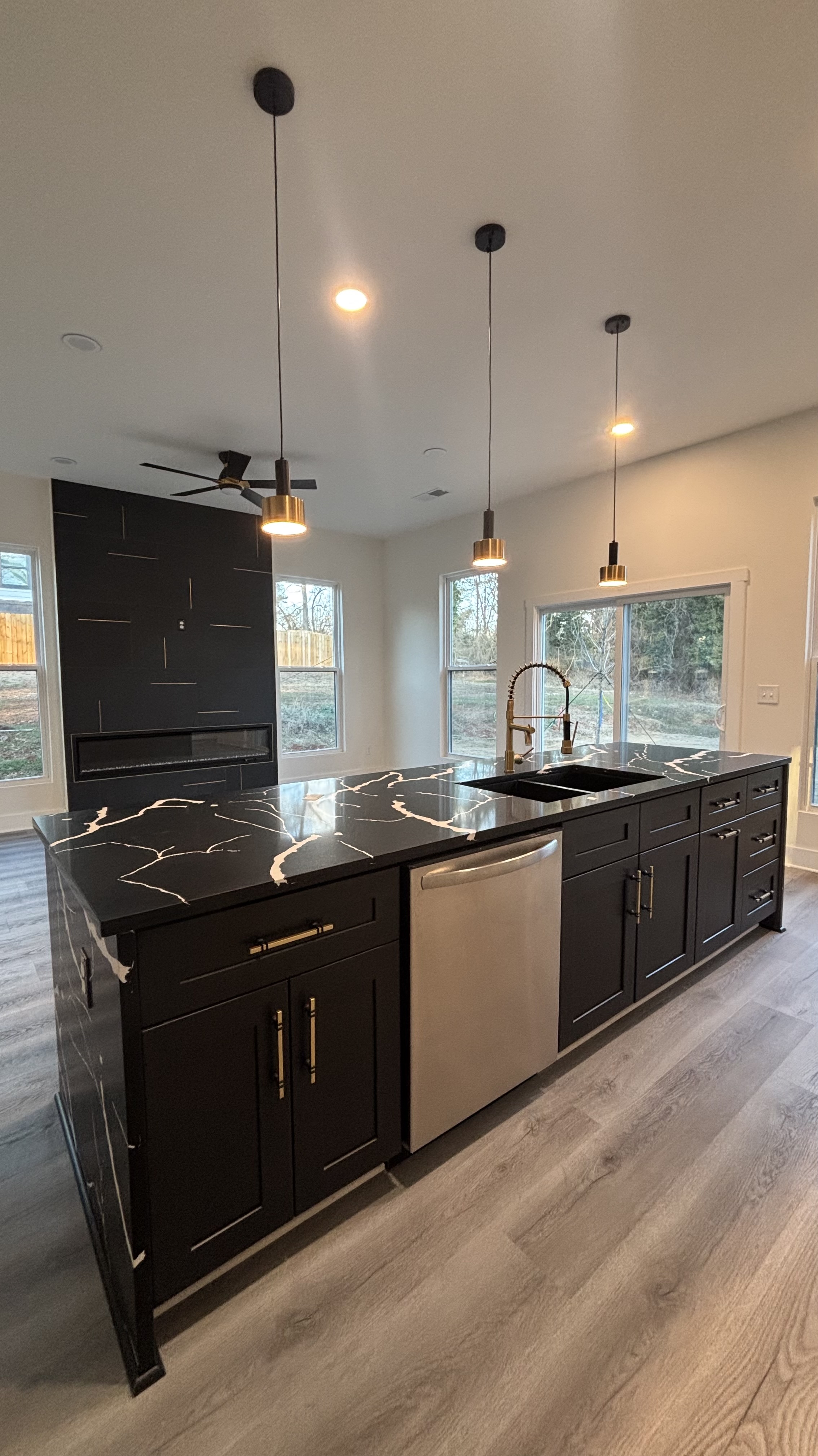 Modern kitchen remodel with dark black cabinetry and gold quartz countertop