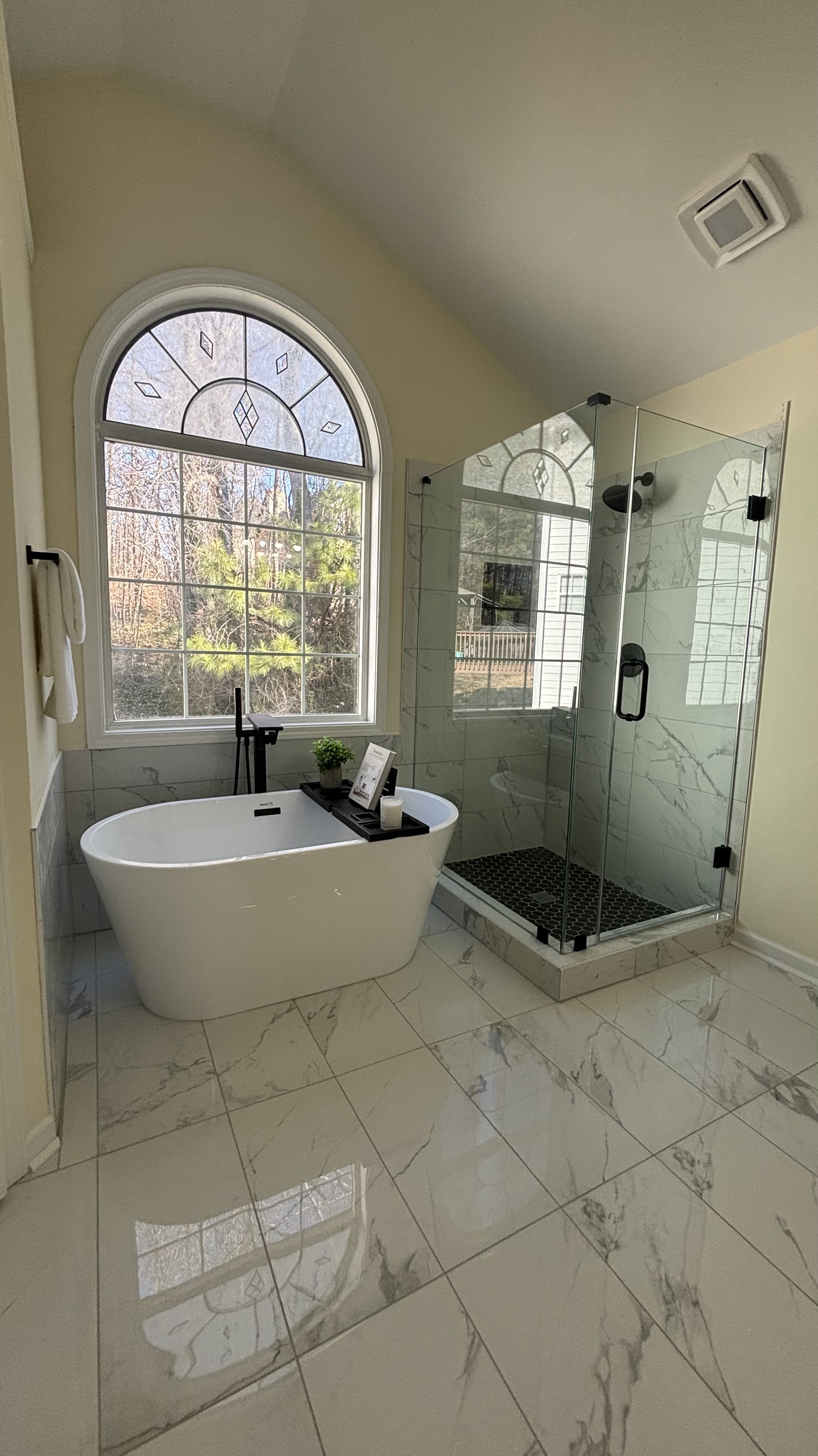 Spa-style bathroom with freestanding soaking tub, glass shower, and marble tile