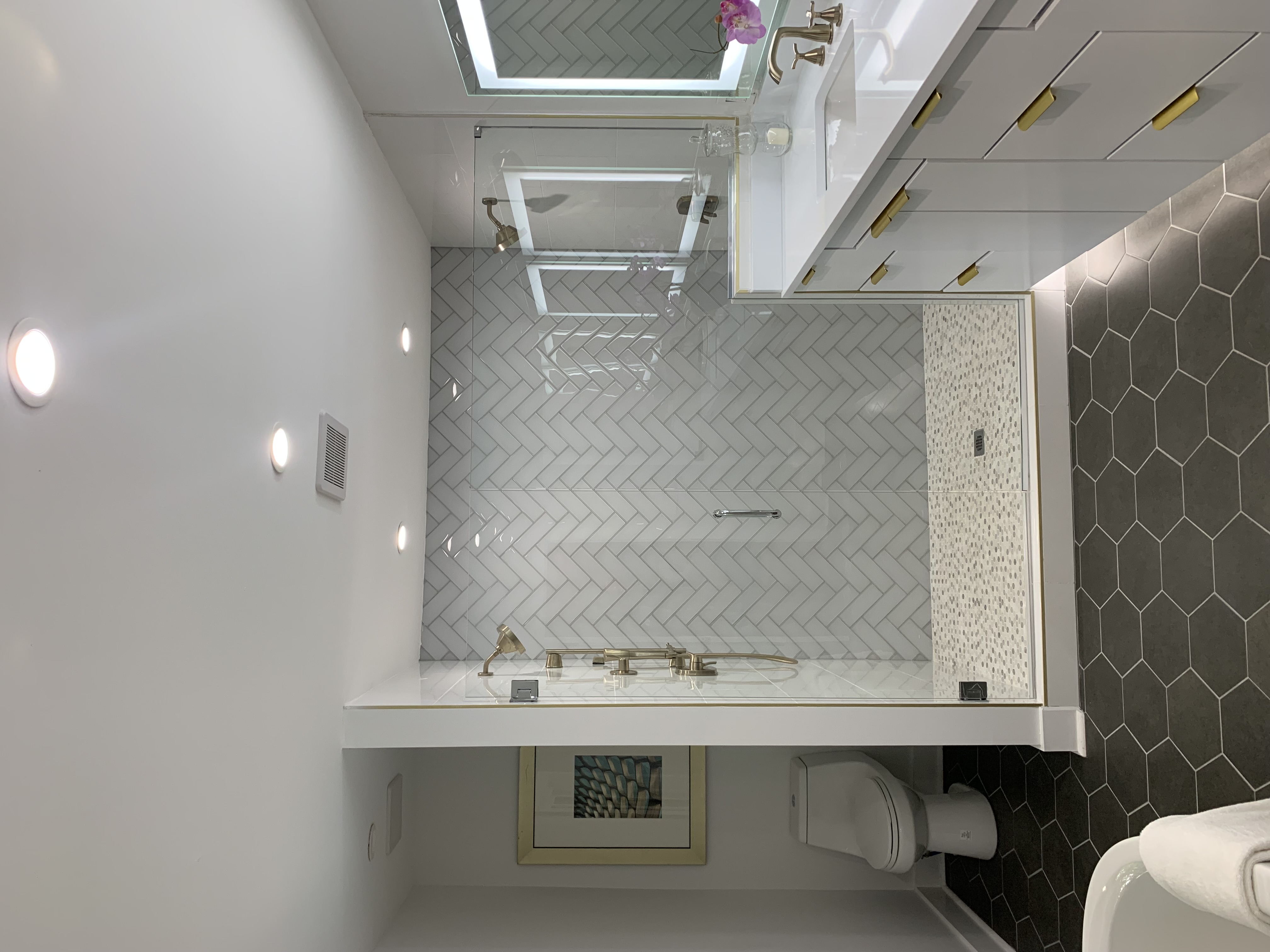Custom tile bathroom showing herringbone white tile and hexagon mosaic patterns