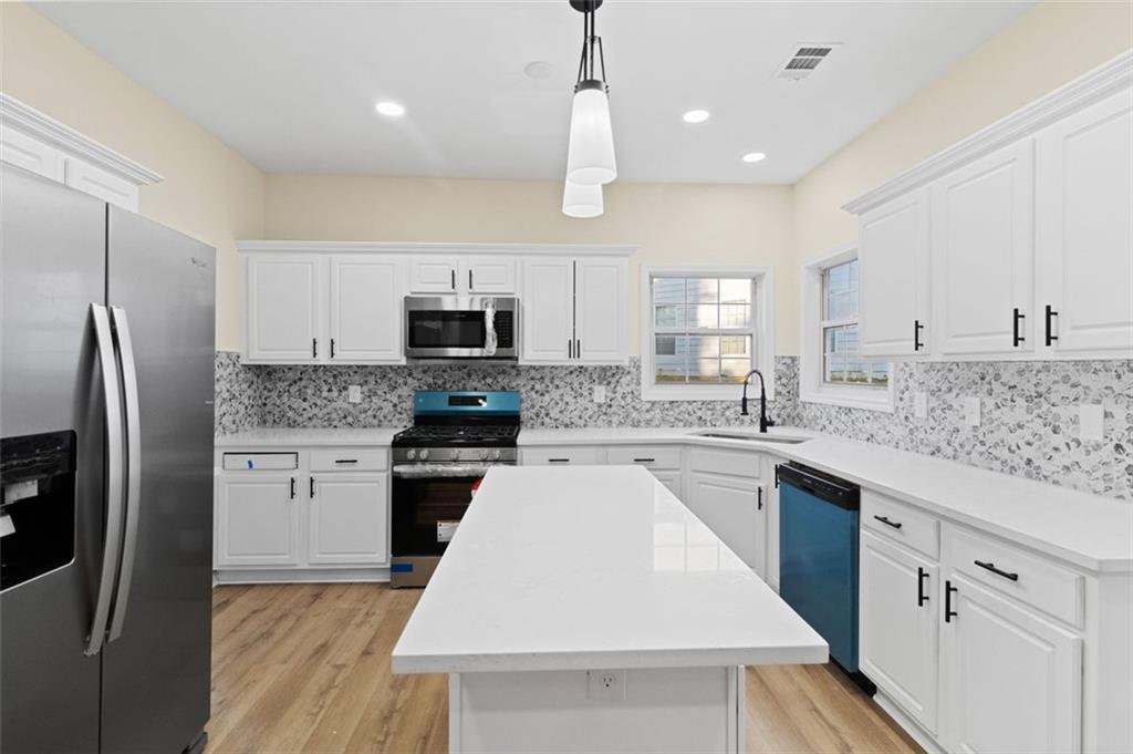 Modern kitchen renovation with white cabinets, quartz island and custom tile backsplash